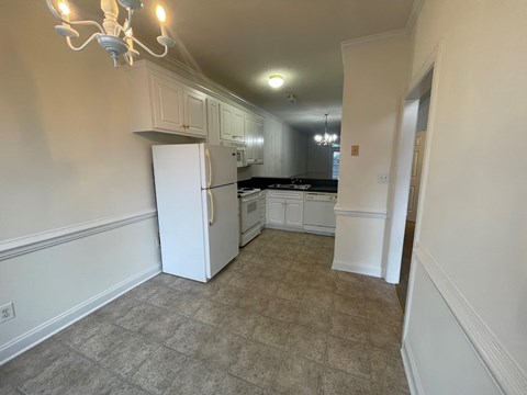 A kitchen with a white refrigerator and cabinets.