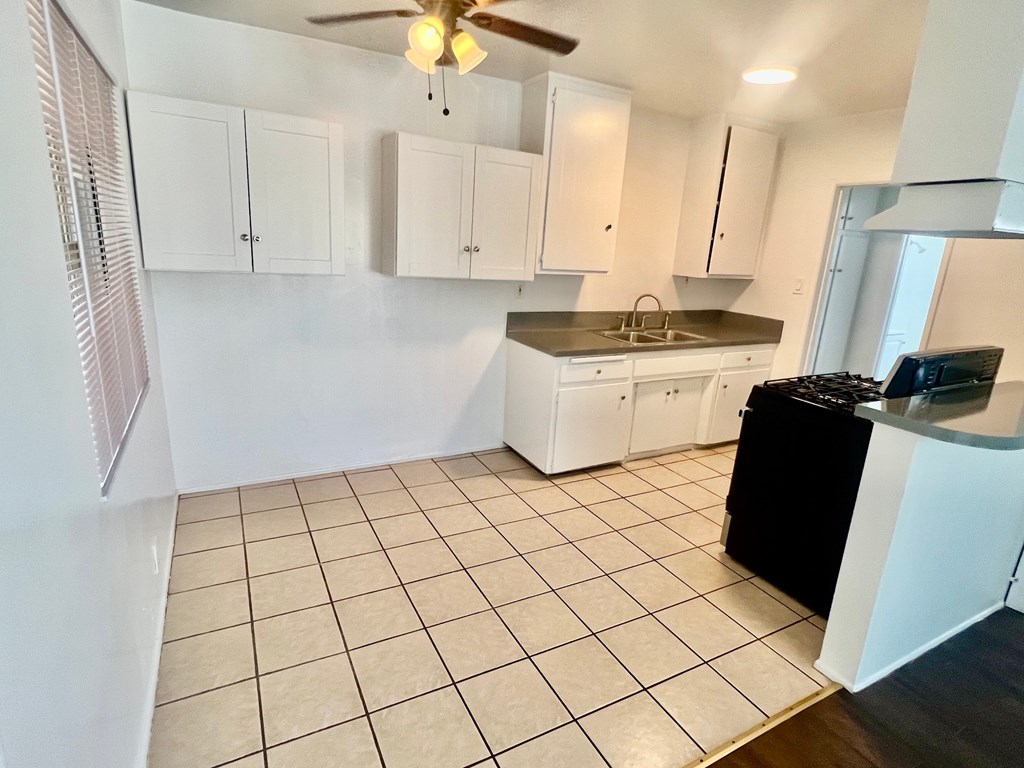 A kitchen with white cabinets and a black dishwasher.