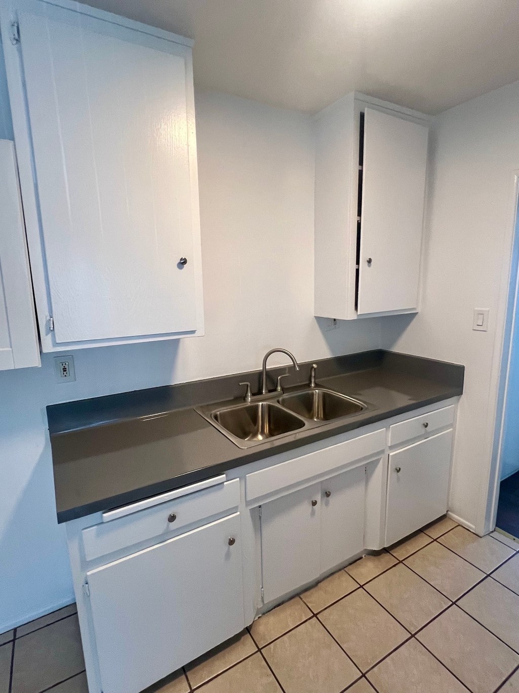 A kitchen with white cabinets and a sink.