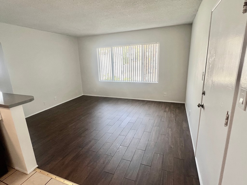 A room with a wooden floor and a window with blinds.