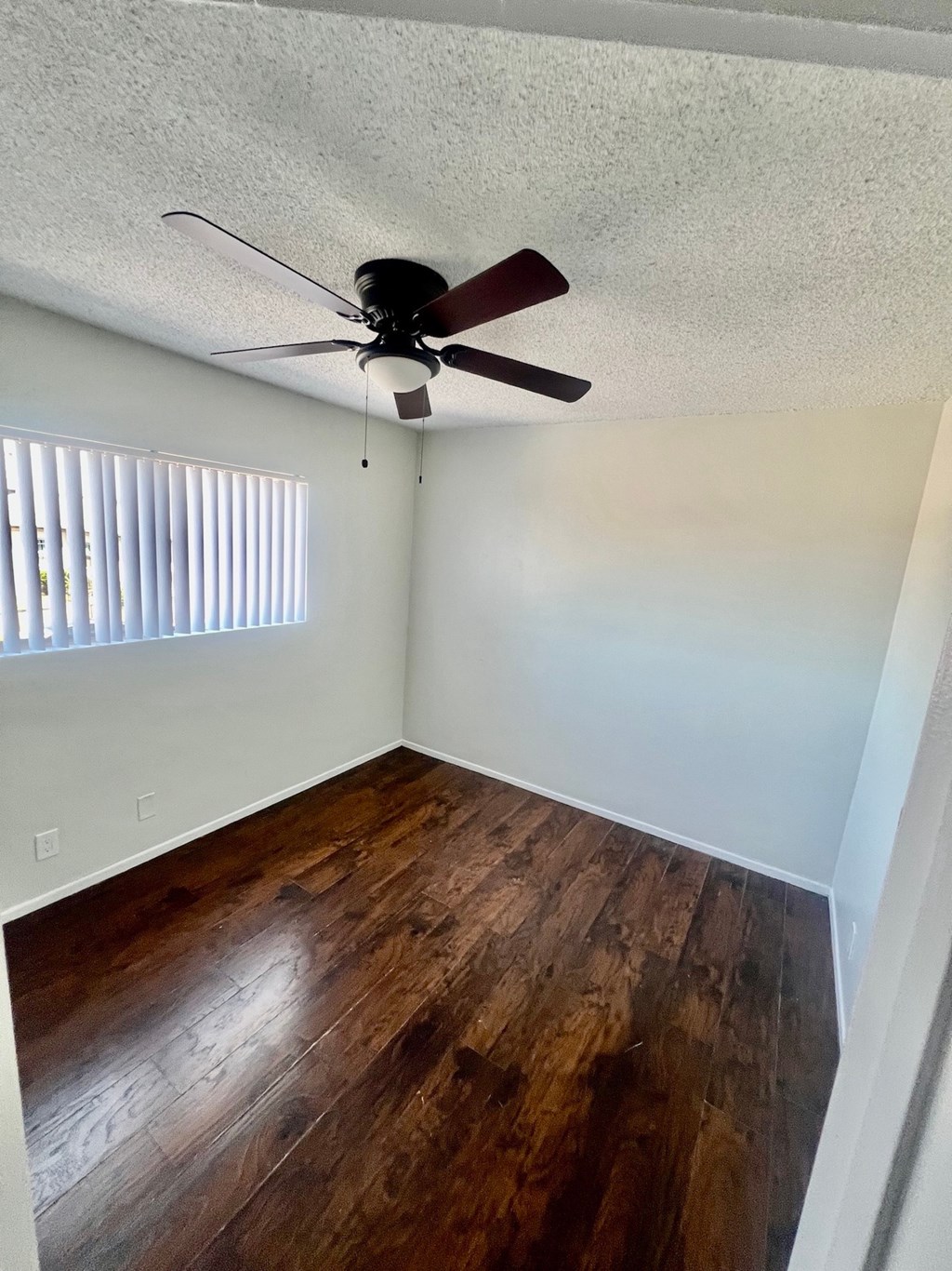 A room with a ceiling fan and wooden flooring.