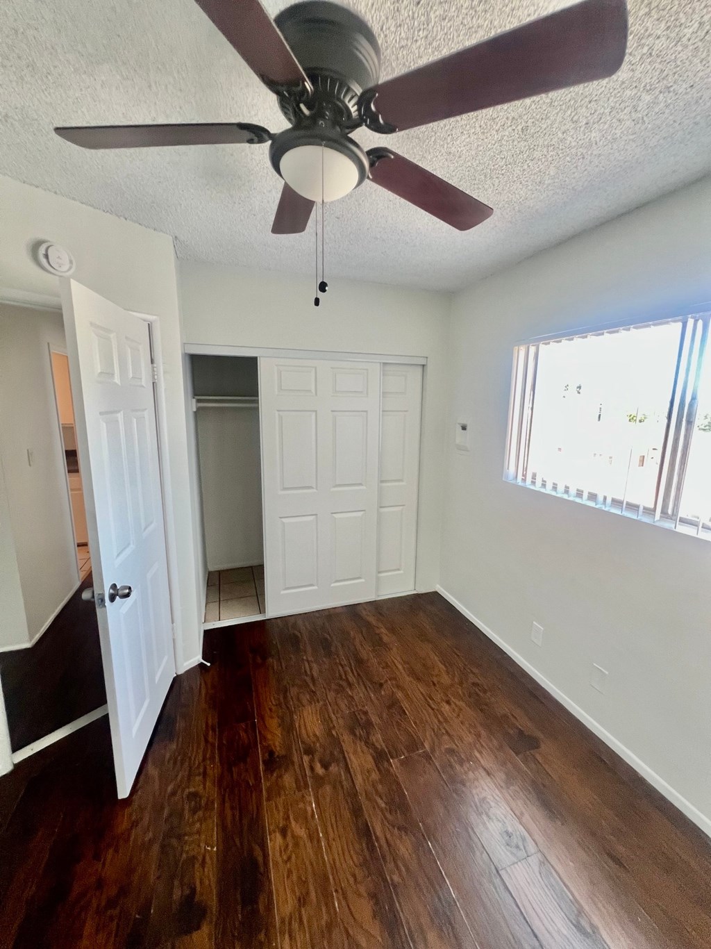 A room with a ceiling fan and wooden floors.