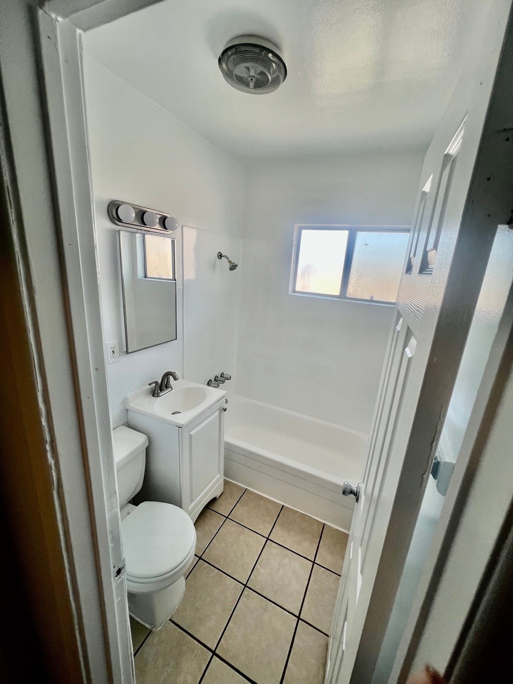 A white bathroom with a toilet, sink, and shower.