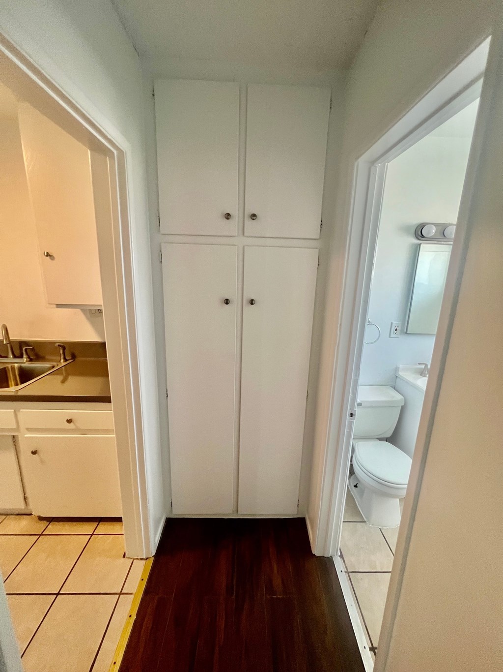 A white kitchen with a white toilet and a white cabinet.