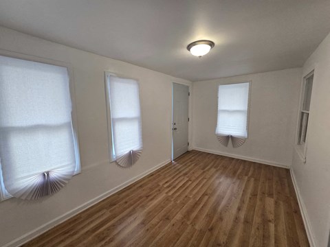 an empty living room with three windows and a wood floor