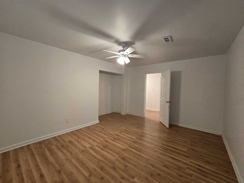 an empty living room with a ceiling fan and wood floors