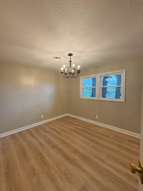 an empty living room with wooden floors and a chandelier