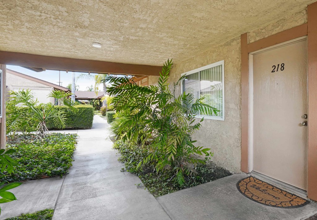 A brown door with a doormat in front of a house.