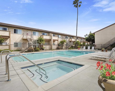 A pool surrounded by chairs and a building in the background.