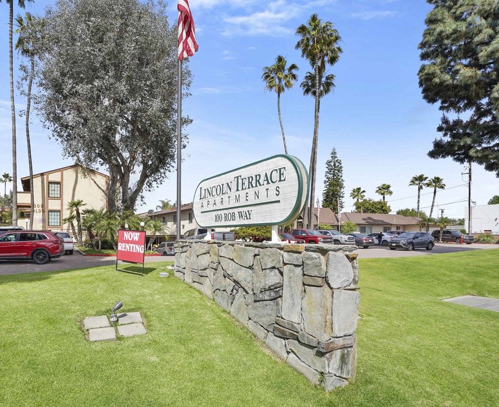 A sign for Lincoln Terrace Apartments stands in front of a stone wall.