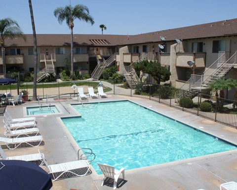 A swimming pool surrounded by white lounge chairs and palm trees.