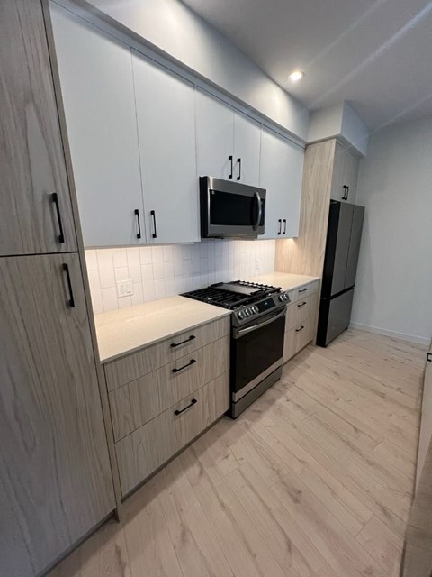 A kitchen with wooden cabinets and a black microwave.