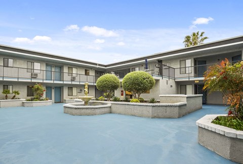 A courtyard with a fountain and a small tree in the middle.
