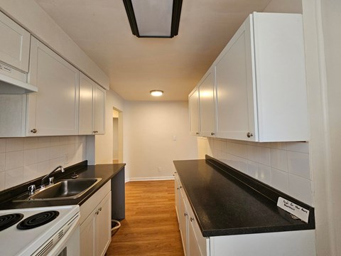 A kitchen with white cabinets and black countertops.