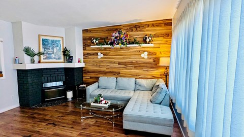 A living room with a grey couch and a wooden wall.