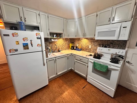A white refrigerator with a green towel on the stove in a kitchen.