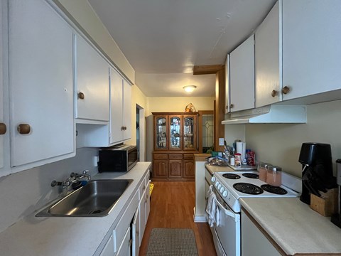 A kitchen with white cabinets and a wooden floor.