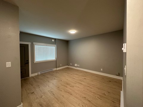 A room with wooden flooring and a window with blinds.