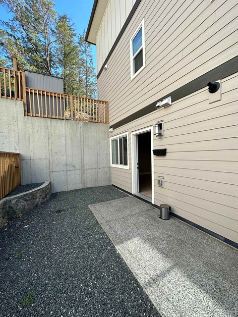 A concrete patio area in front of a house with a door and a window.
