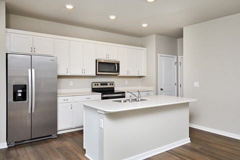 A kitchen with white cabinets and a stainless steel refrigerator.