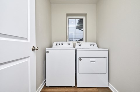 Two white front load washing machines in a laundry room.