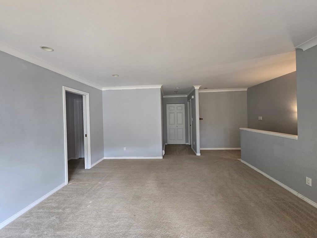 A spacious room with carpeted floor and white walls.