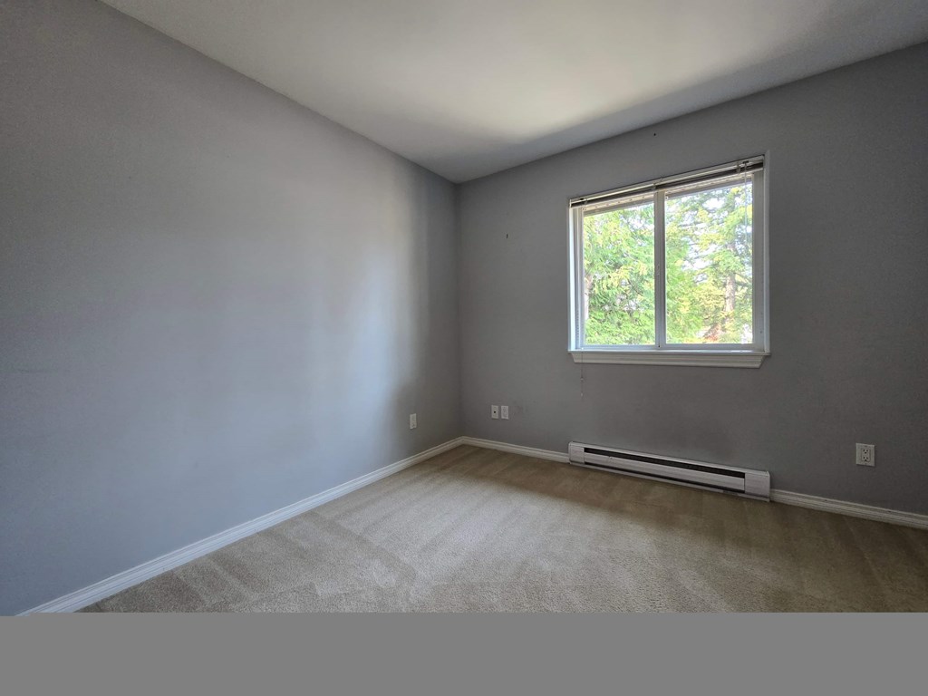 A room with a window and a radiator on the floor.
