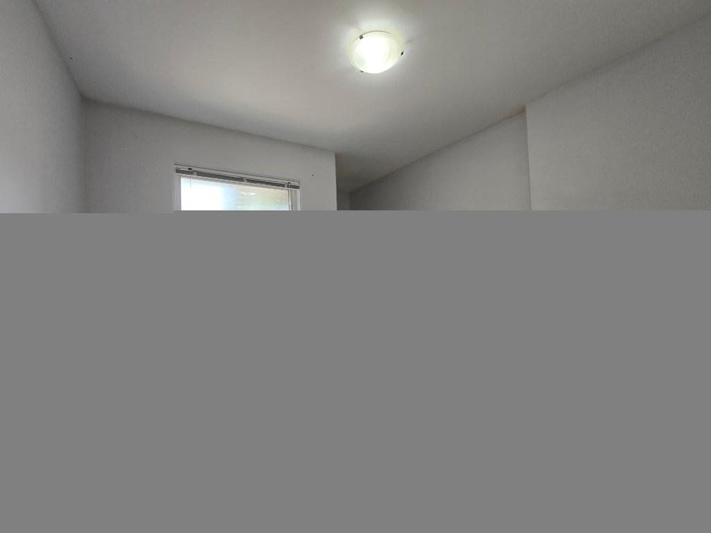 A room with a window and a light on the ceiling.