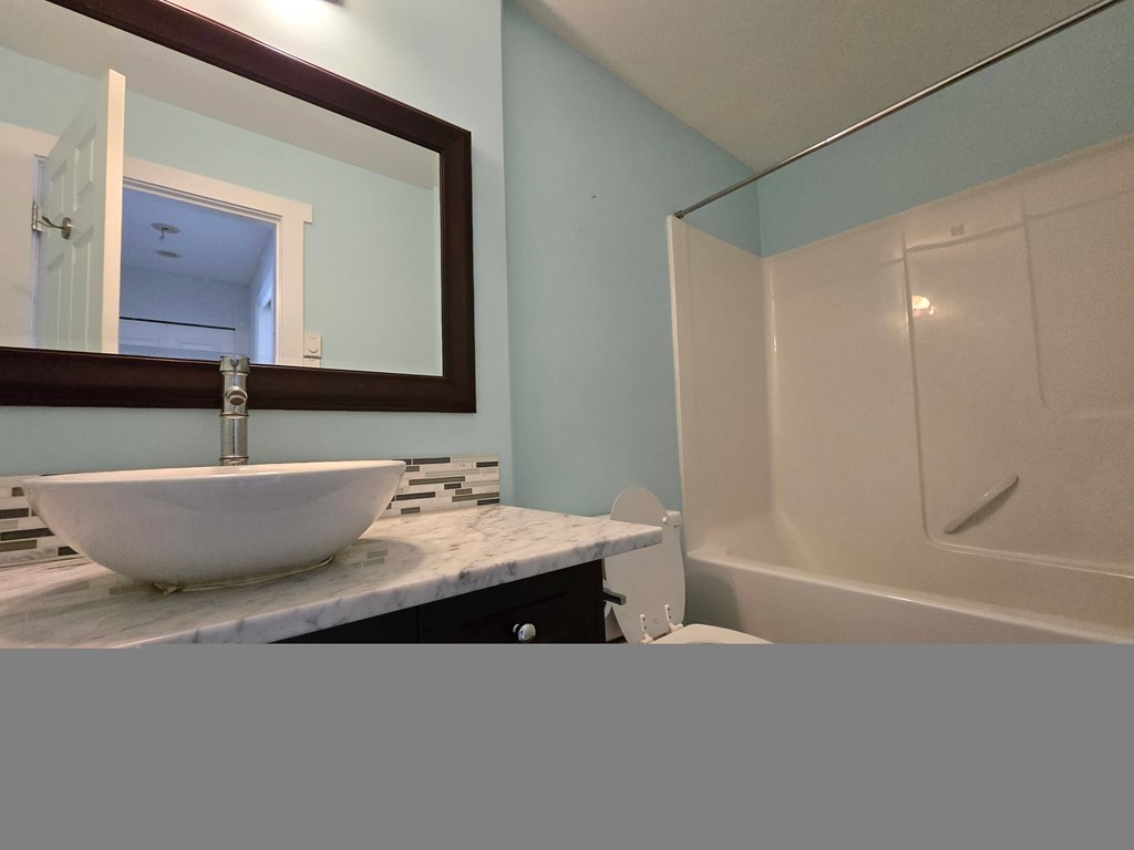 A white sink is on a marble countertop in a bathroom.