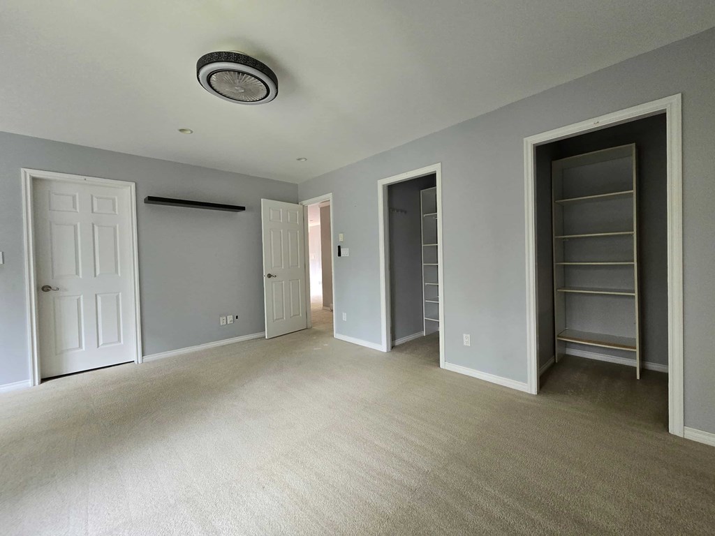 A room with a carpeted floor and a ceiling fan.