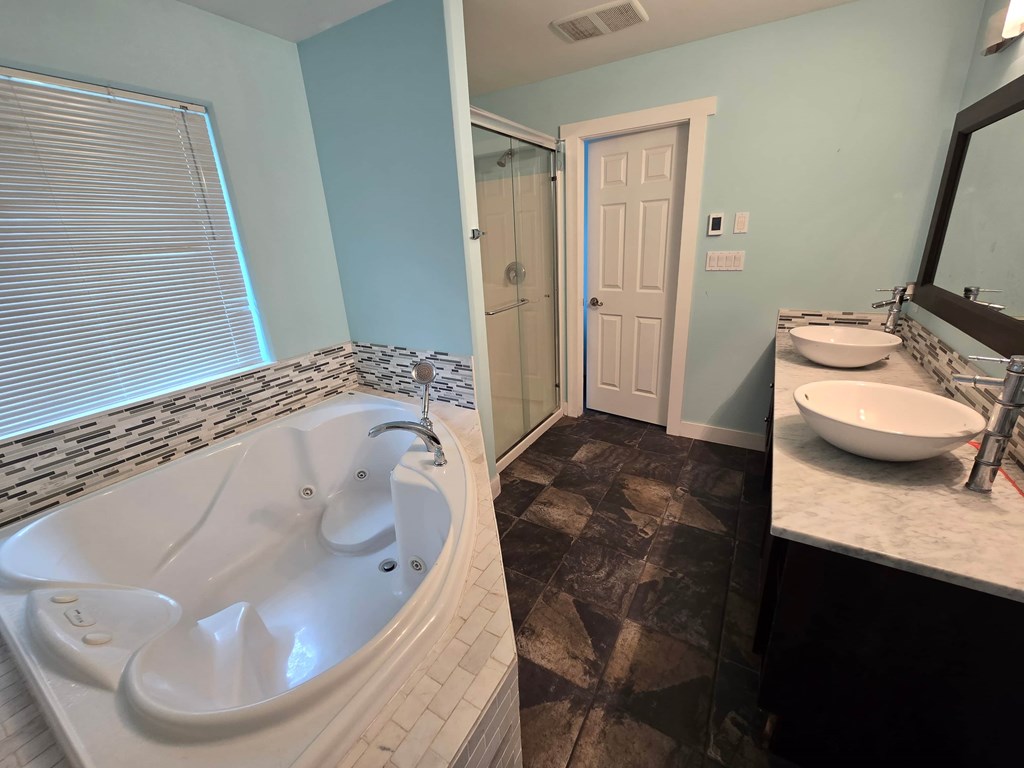 A white bathtub with a shower head and a white sink with a black counter.