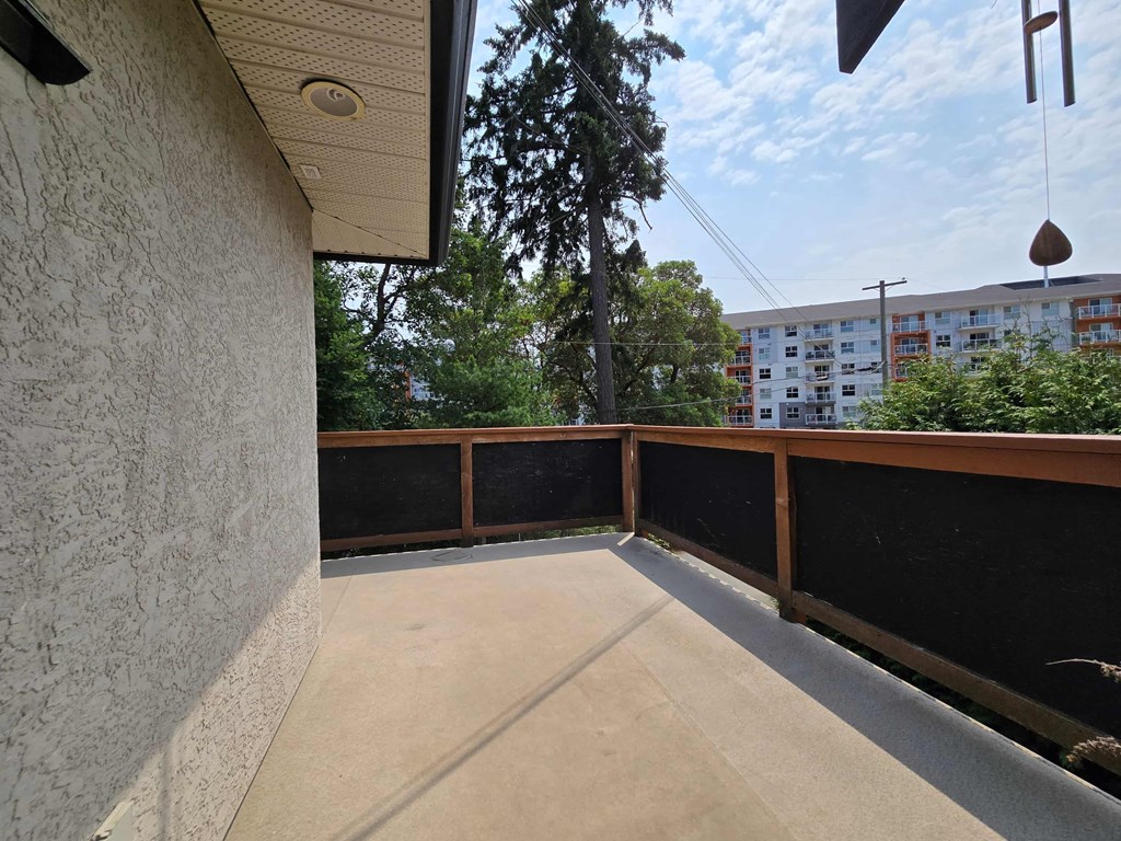 A balcony with a concrete floor and a wooden railing.