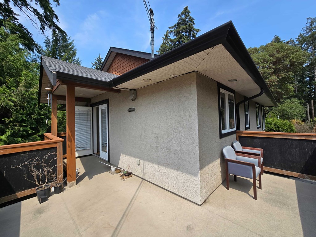 A small house with a porch and a tree in the background.