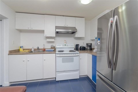 A kitchen with white cabinets and a stainless steel refrigerator.