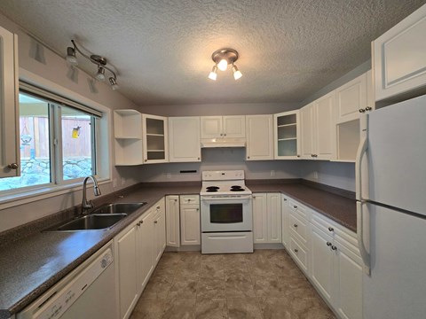 A kitchen with white cabinets and appliances.