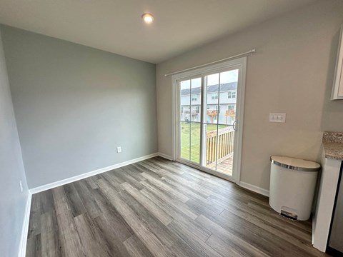 a living room with a door to a balcony and wood flooring
