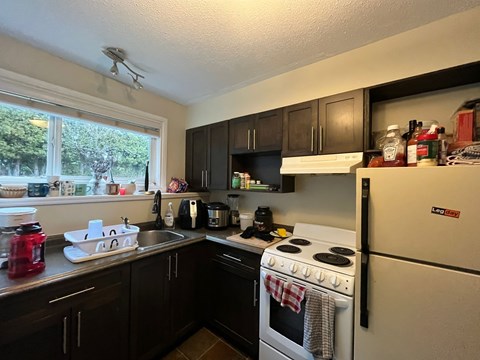 A kitchen with a white stove and black cabinets.