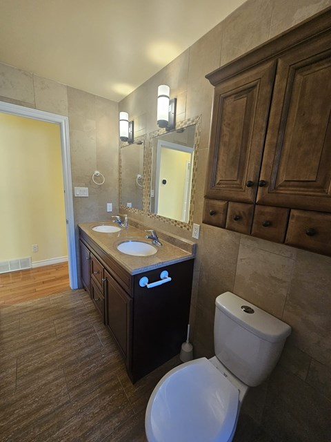 A bathroom with a toilet, sink, and mirror.