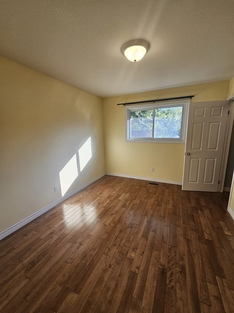 A room with wooden flooring and a window with blinds.