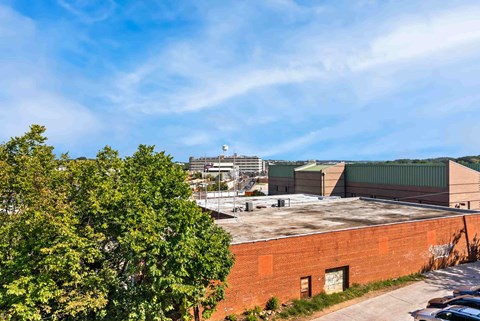 A view of a building with a parking lot in front and trees on the left.