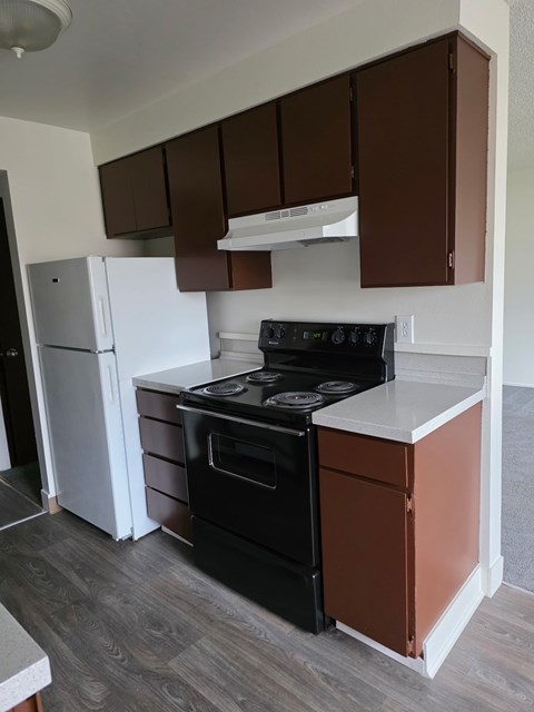 A kitchen with brown cabinets and a black stove top oven.