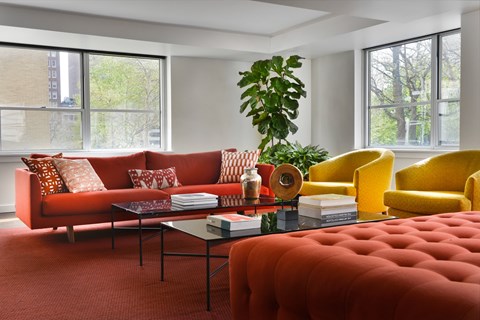 a living room with orange couches and yellow chairs and a table
