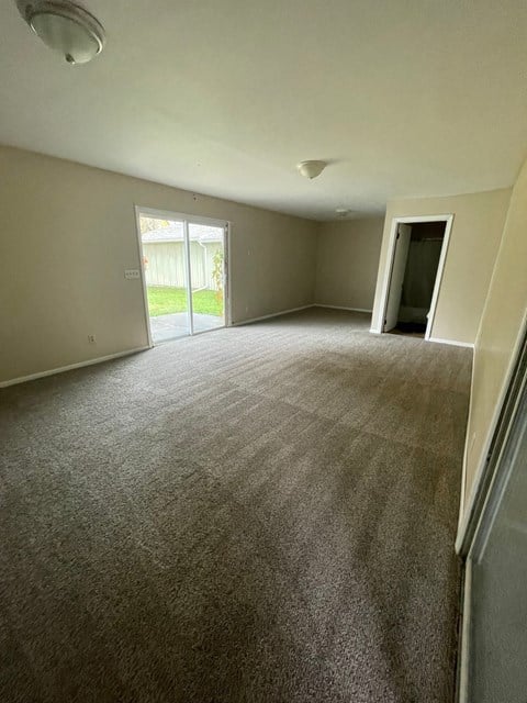 an empty living room with carpet and a door to a yard
