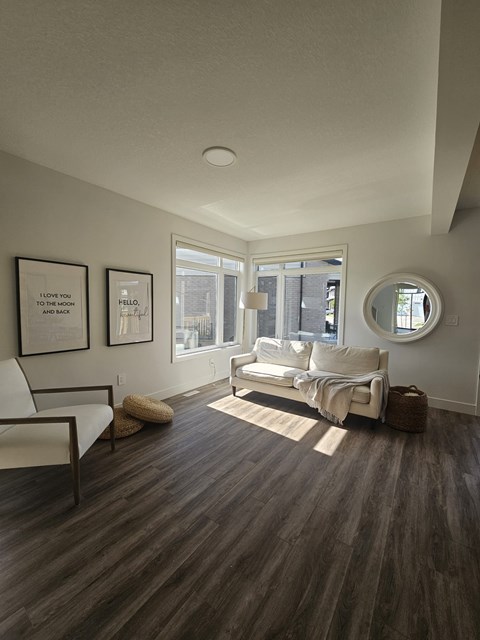 A living room with a white couch and a round mirror on the wall.