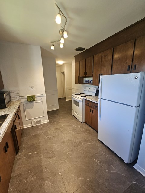 A kitchen with a white refrigerator and wooden cabinets.