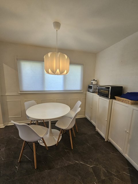 A dining room with a white table and chairs.