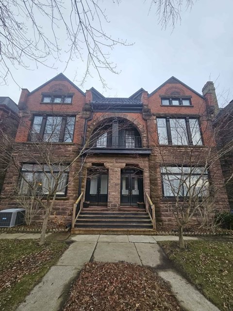 A large red brick house with a black front door and steps leading up to it.