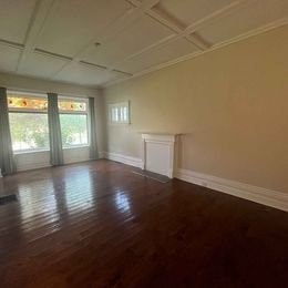 A room with wooden floors and a window with curtains.