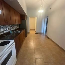 A kitchen with a white stove top oven and a tiled floor.