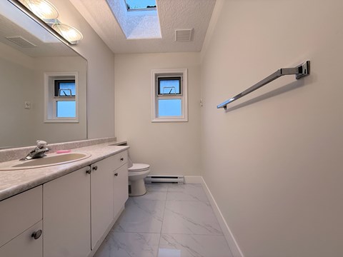 A bathroom with a toilet, sink, and mirror.